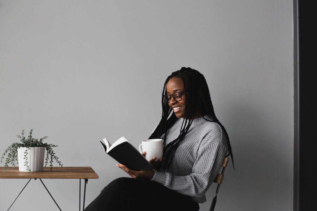 Woman sitting on a chair reading a book with a cup of coffee - Photo by Alexandra Fuller on Unsplash