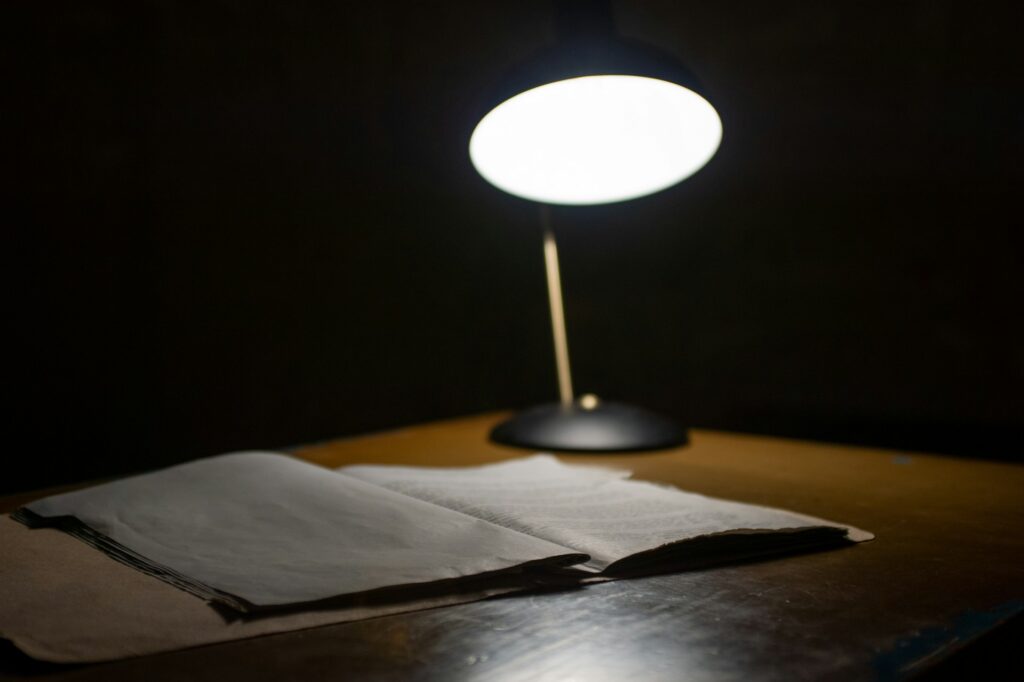 A light illuminating a notebook on a desk - Photo by 𝓴𝓘𝓡𝓚 𝕝𝔸𝕀 on Unsplash 