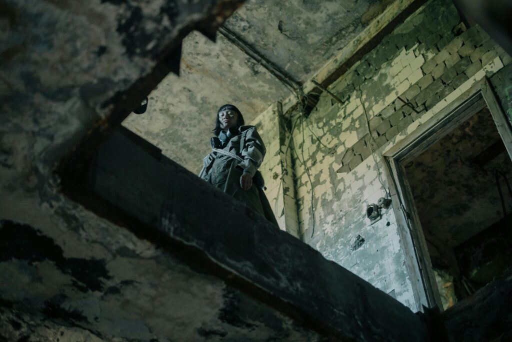 A woman staring down off a balcony into a ruined. building - Dystopian fiction - Photo by cottonbro studio for Pexels